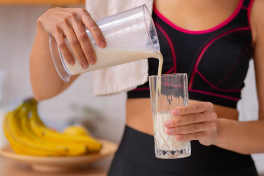 A woman pouring a protein shake post workout.
