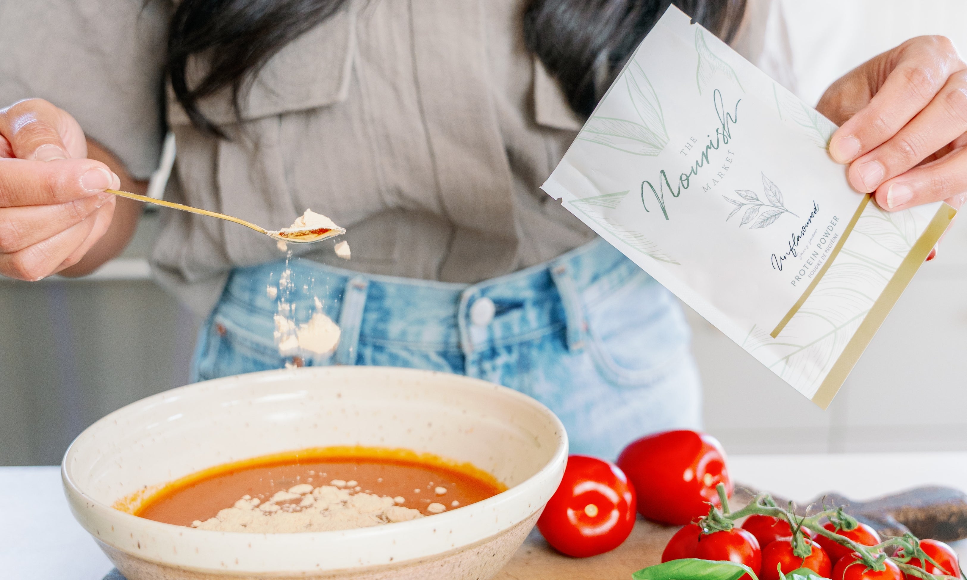 A woman sprinkling in unflavoured protein powder into a tomato soup. 